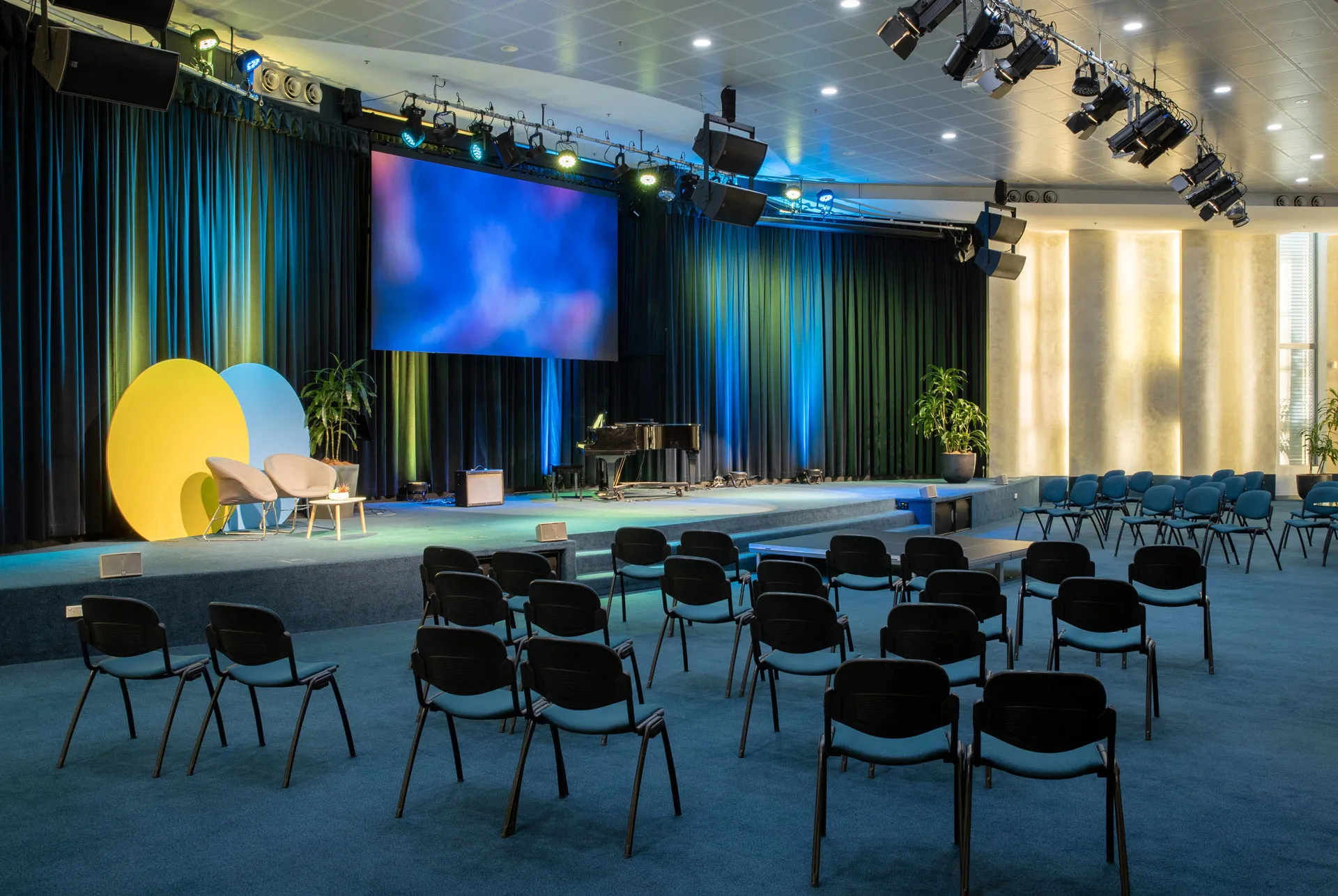 Interior of the Northside Conference Centre main auditorium with tiered seating facing a large stage and screen